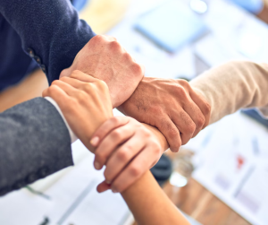 An images of students joining hands to create a sign of unity through their studies.